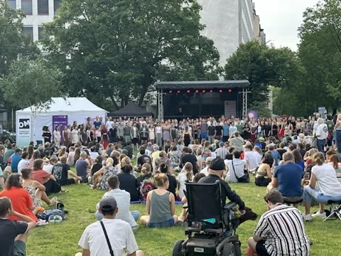 Gäste verfolgen ein Bühnenprogramm unter freiem Himmel